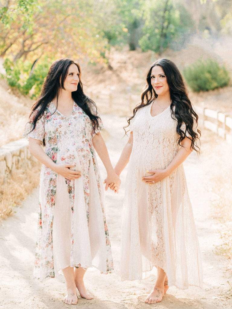 Twin moms to be holding hands and walking down a path Santa Monica Women's Health