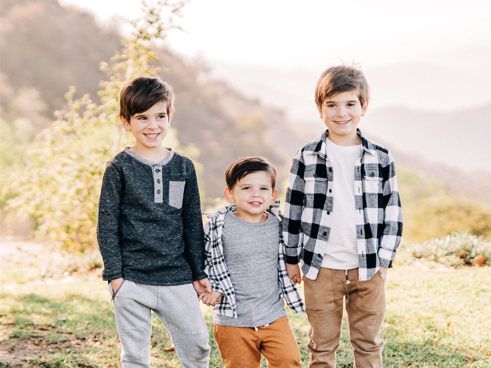 3 brothers in neutral clothing standing hand in hand in a field Pediatrician Calabasas