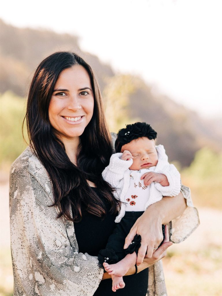 mom holding a newborn baby in her arms in a field Pediatrician Calabasas