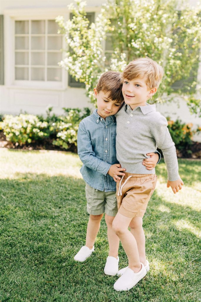 two brothers wearing blue button down shirts hugging in the front yard