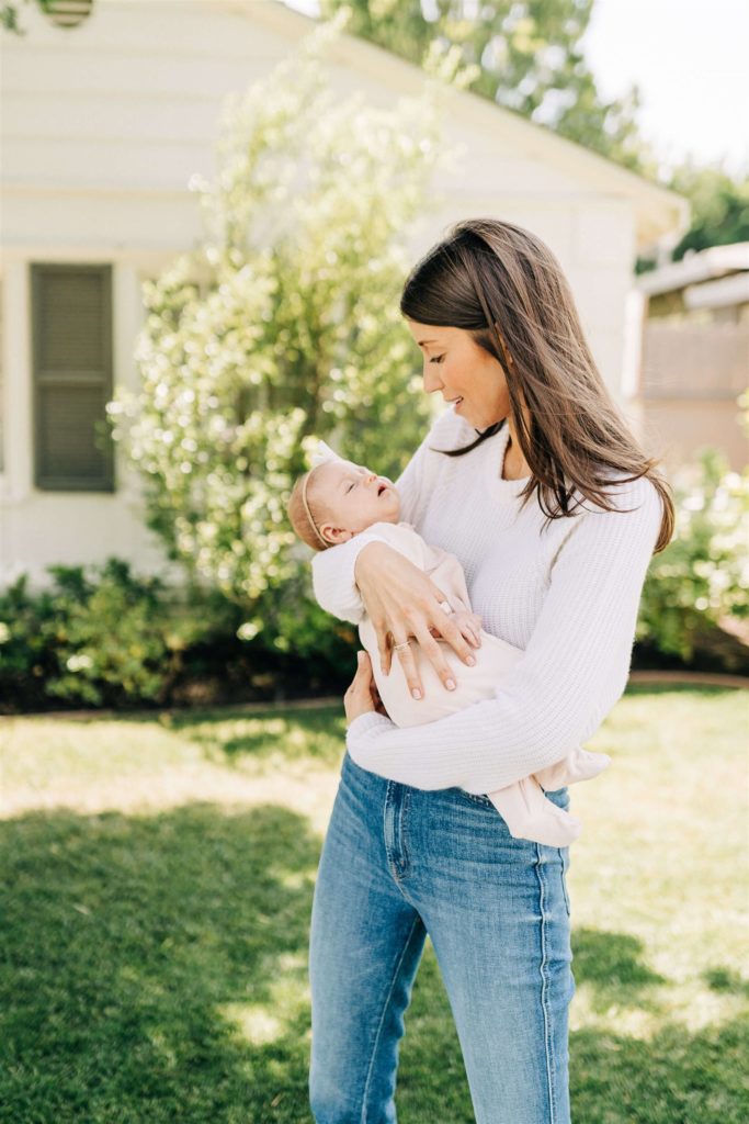 new mom in white shirt holding her new baby outside of her house Pediatrician Sherman Oaks