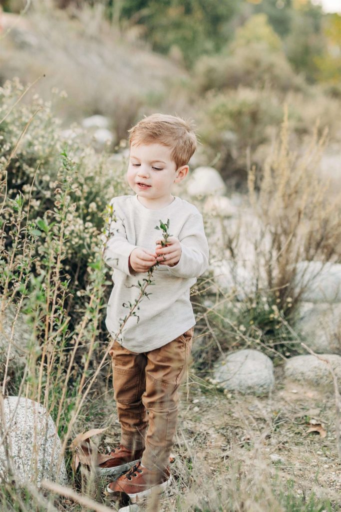 little boy playing with plants in the desert