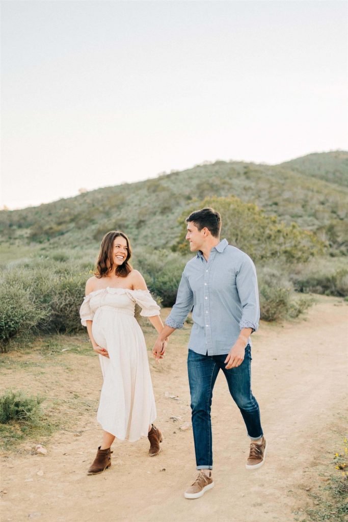 pregnant woman in cream maternity dress walking with her husband Ventura Yoga Studios